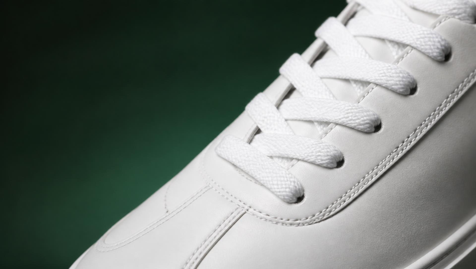 Macro detail of white sneaker laces against a deep green backdrop